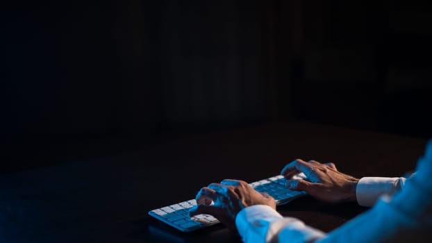 Close-up of male hands on a keyboard in the dark.