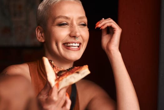 Pizza is happy food. a young woman enjoying a slice of pizza in a cafe.