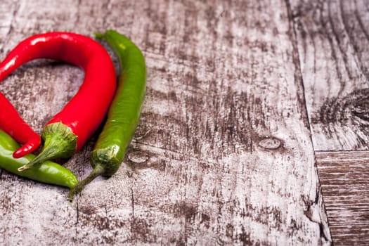 Green and red spicy papper on wooden background