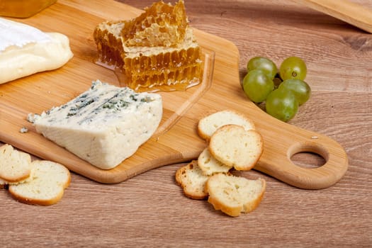 Honey, white cheese and other cheese with grape on wooden backgr