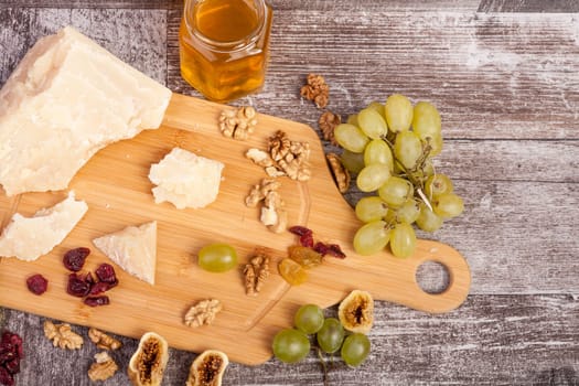 Grape, nuts, honey and cheese on wooden background