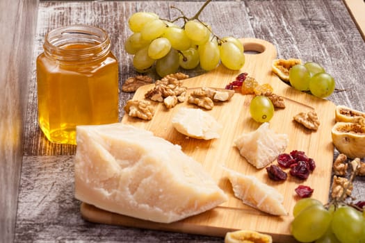 Cheese, honey and grape on wooden background