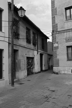 Vertical black and white shot of an old town alley in Alcala de Henares, Spain