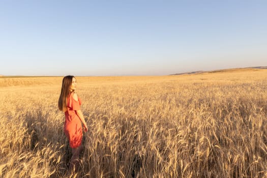 Young woman in the wheat field, mental and physical wellbeing concept. Copy space.