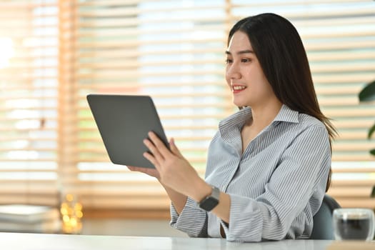 Attractive asian female marketing business manager expert using digital tablet at her working desk I bright office