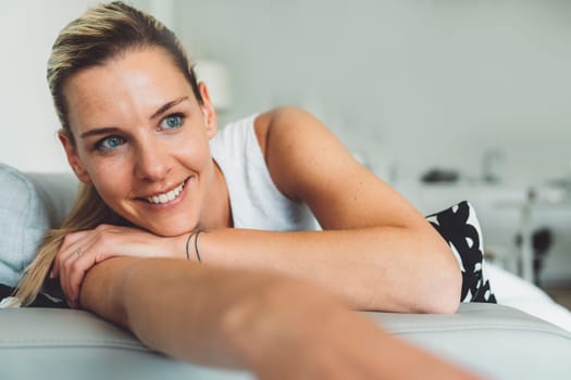 Smiling portrait of a woman with blue eyes laying on the sofa relaxing at home