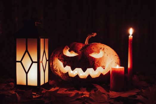 Dark spooky photo of jack-o-lantern with candles and lantern nearby