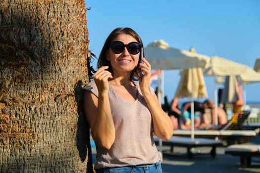 Portrait of smiling woman relaxing in resort hotel using smartphone