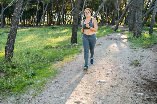 Overweight young woman jogging in street or public park, copy space and empty space for text. Weight loss and fitness concept