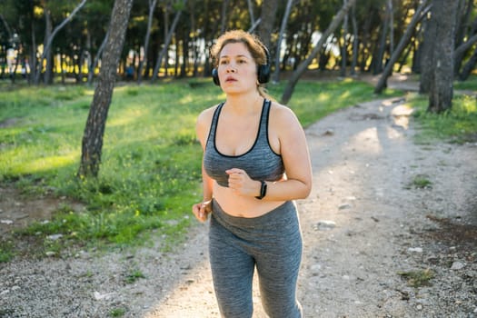 Overweight young woman jogging in street or public park, copy space and empty space for text. Weight loss and fitness concept