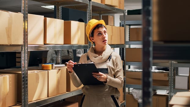 Young woman writing stock logistics in warehouse