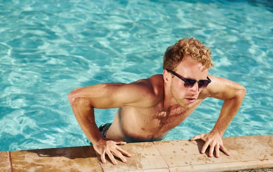 Man in black sunglasses is in swimming pool at his vacations