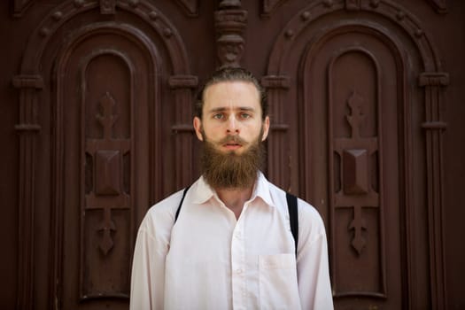 Portrait of bearded hipster in front of a door