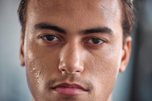 Portrait, sweat and intense with a sports man closeup in the gym for a cardio or endurance workout. Fitness, exercise and focus with a male athlete taking a break after health training for wellness