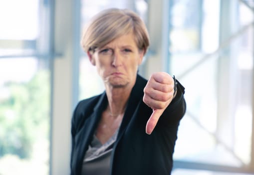 Better luck next time. Portrait of a mature businesswoman showing thumbs down in an office.