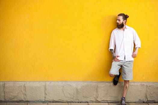 Cool tattooed bearded hipster on yellow wall