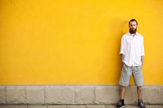 Tattooed bearded hipster on yellow wall