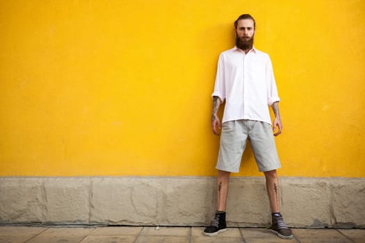 Cool Tattooed bearded hipster on yellow wall