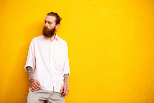 Tattooed bearded man on yellow wall