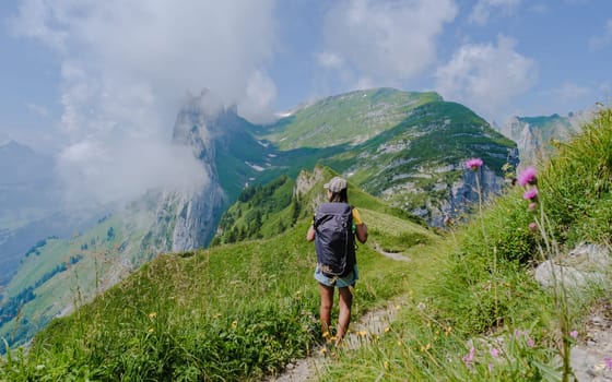 Asian women hiking in the Swiss Alps mountains at summer vacation with a backpack and hiking boots