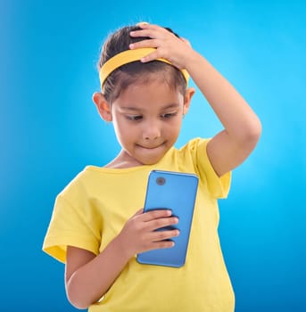 Phone, stress and child worry on blue background with mistake, accident and guilty expression in studio. Technology, smartphone and young girl with anxiety, stressed out and worried for trouble