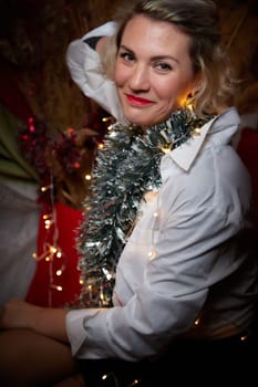 Portrait of a beautiful laughing funny blonde girl with light of garland on a dark background before Christmas or New Year