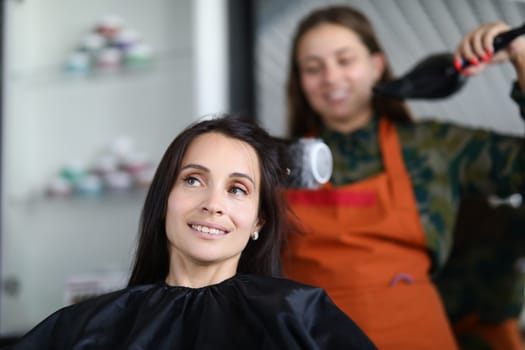 Hairdresser drying hair woman client in hairdressing beauty salon