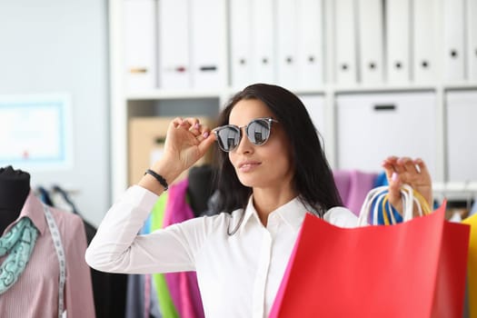 Stylish woman in sunglasses holding shopping bags