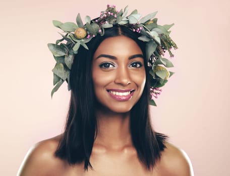 She was blessed with beauty to rival mother nature. Studio portrait of a beautiful young woman wearing a wreath while posing against a pink background.