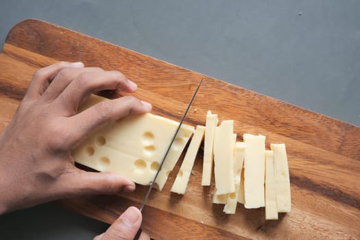 cutting cheese with knife on a chipping board