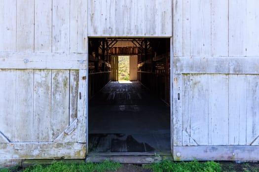 Open barn door with dark interior and bright exterior on historic cattle ranch
