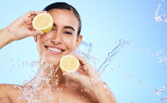 Beauty, lemon and water splash with portrait of woman in studio for natural cosmetics, nutrition and detox. Glow, fruits and hydration with female on blue background for diet, clean face and skincare