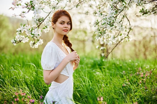 beautiful young readhead woman standing near the apple tree