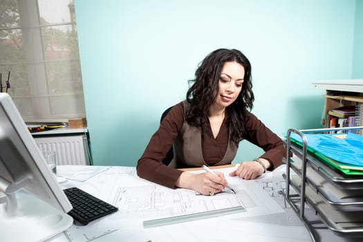 Architect woman at her working desk with blueprints in front