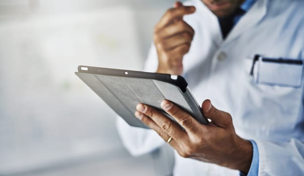 Technology is such a vital tool in the workplace. Closeup shot of an unrecognizable doctor working on a digital tablet