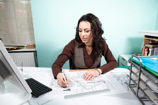 Woman on working desk with blueprints in front