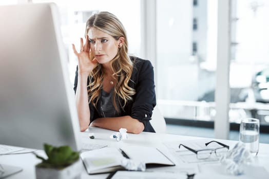 One demanding email after another. a young businesswoman experiencing stress while working at her desk in a modern office.