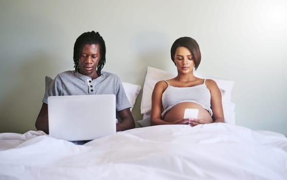 Connecting with everyone but each other. a couple sitting in bed while using wireless devices.