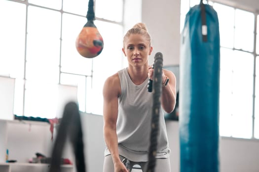 Fitness, focus and battle ropes with a woman in gym for a sports workout to build strong muscles. Exercise, serious and cardio with a female athlete in a wellness studio for endurance training