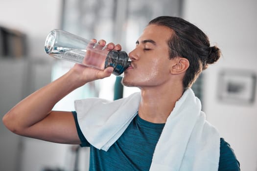 Fitness, man and drinking water for hydration after workout, exercise or intense training at home. Thirsty male resting from sports exercising for hydrated wellness, health and fresh natural drink