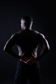 One young african muscular build man standing topless silhouette isolated on black background