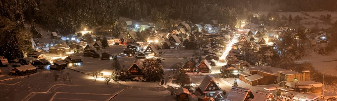 Panoramic view of snow and mist falling on traditional village at night
