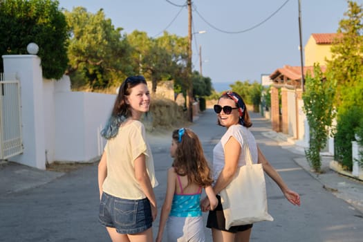 Mother and two daughters teenager and youngest walking together holding hands