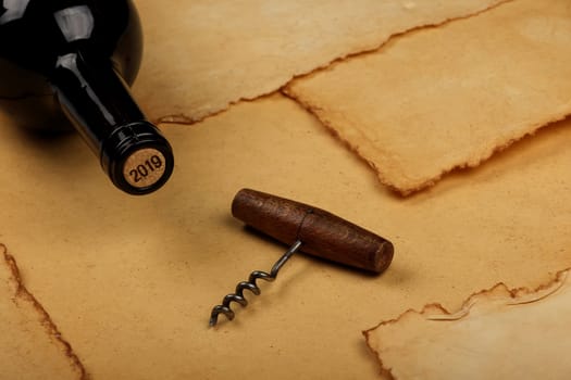 Bottle of wine with cork and opener on brown paper