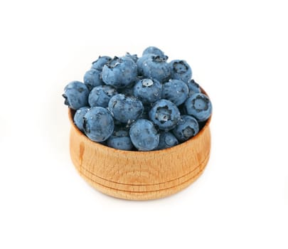 Blueberries in wooden bowl close up over white