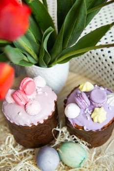 Colorful Easter eggs lie together with Easter pastries decorated with colored chocolate on a wooden table. Easter holiday.