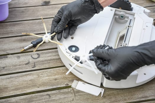 replacing a worn brush on a robot vacuum cleaner, a woman unscrews