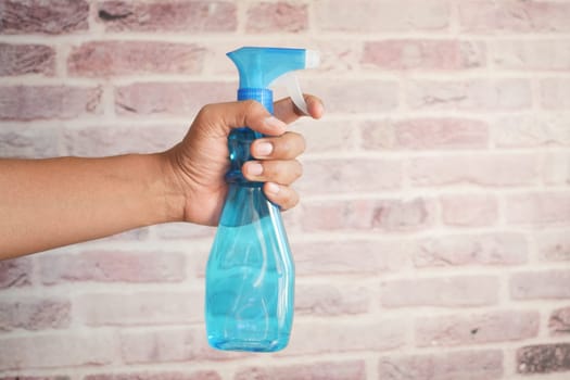 holding a plastic bottle spraying disinfect