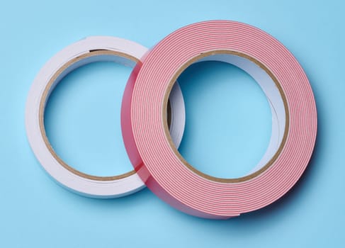 Two rolls of double-sided sticky tape on a blue background, top view