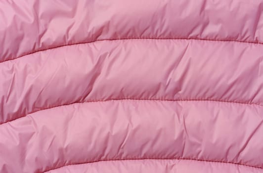 A fragment of pink fabric with down filling and stitching, fabric for jackets and coats